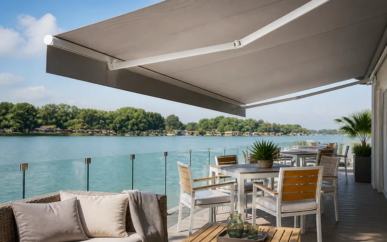 Uitgeschoven grijs knikarmscherm boven een zonnig terras