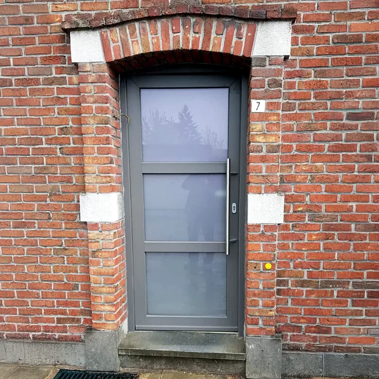 Grijze PVC voordeur op maat in een bakstenen gevel
